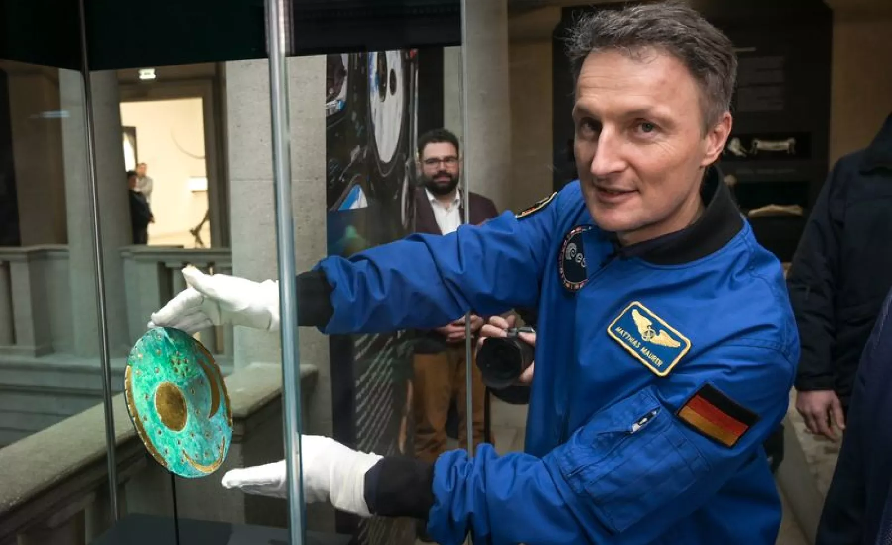 Astronaut Matthias Maurer setzt die Nachbildung der Himmelsscheibe von Nebra in eine Vitrine im Landesmuseum für Vorgeschichte Halle.
