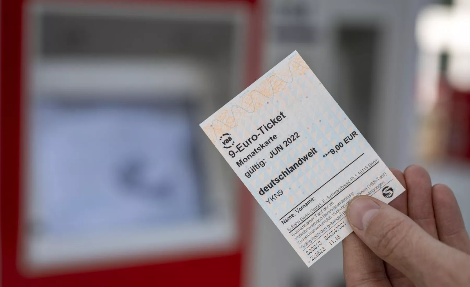Ein 9-Euro-Ticket wird vor einen Fahrkartenautomat gehalten