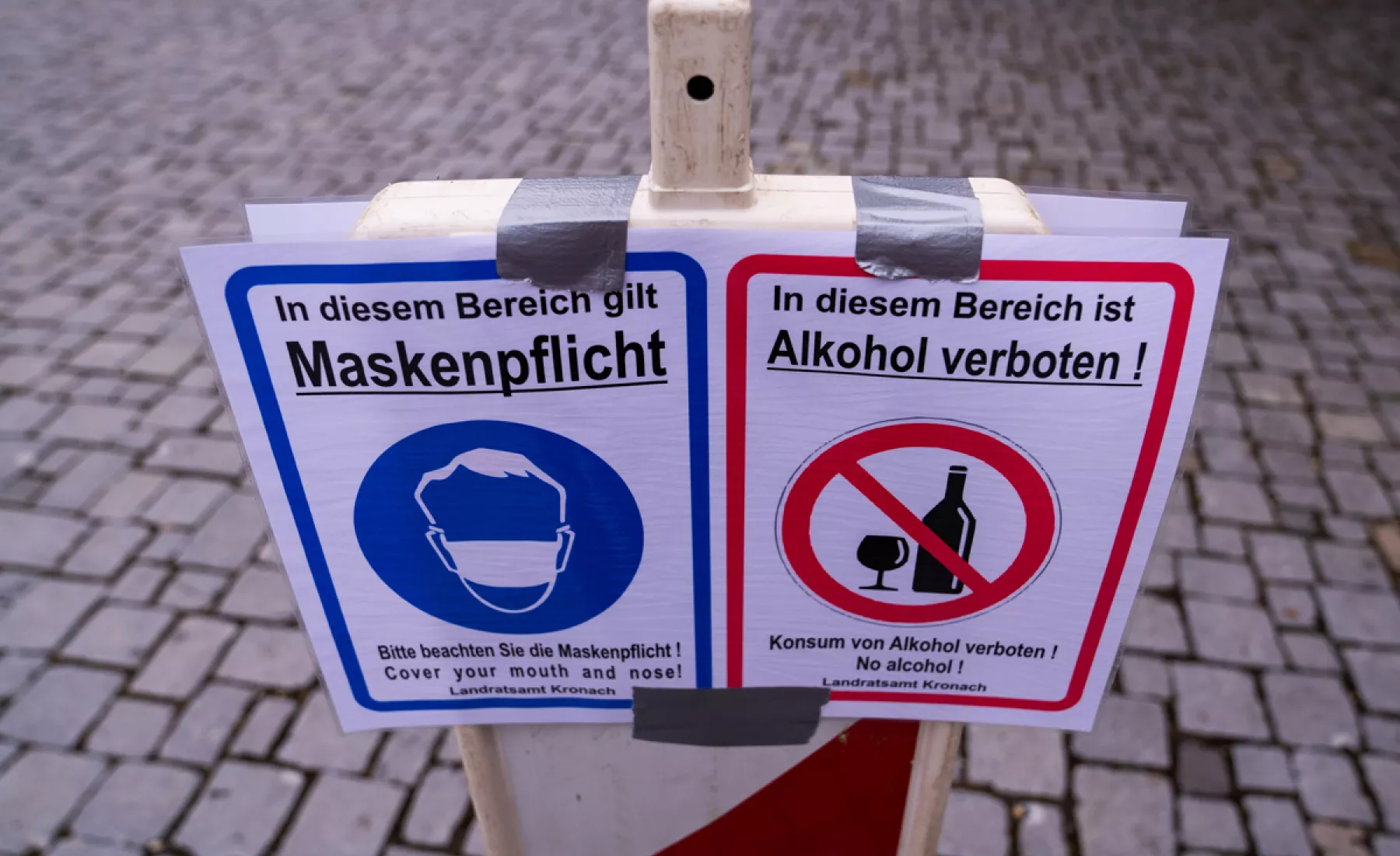 Ein Schild weist auf die Maskenpflicht und das Alkoholverbot hin