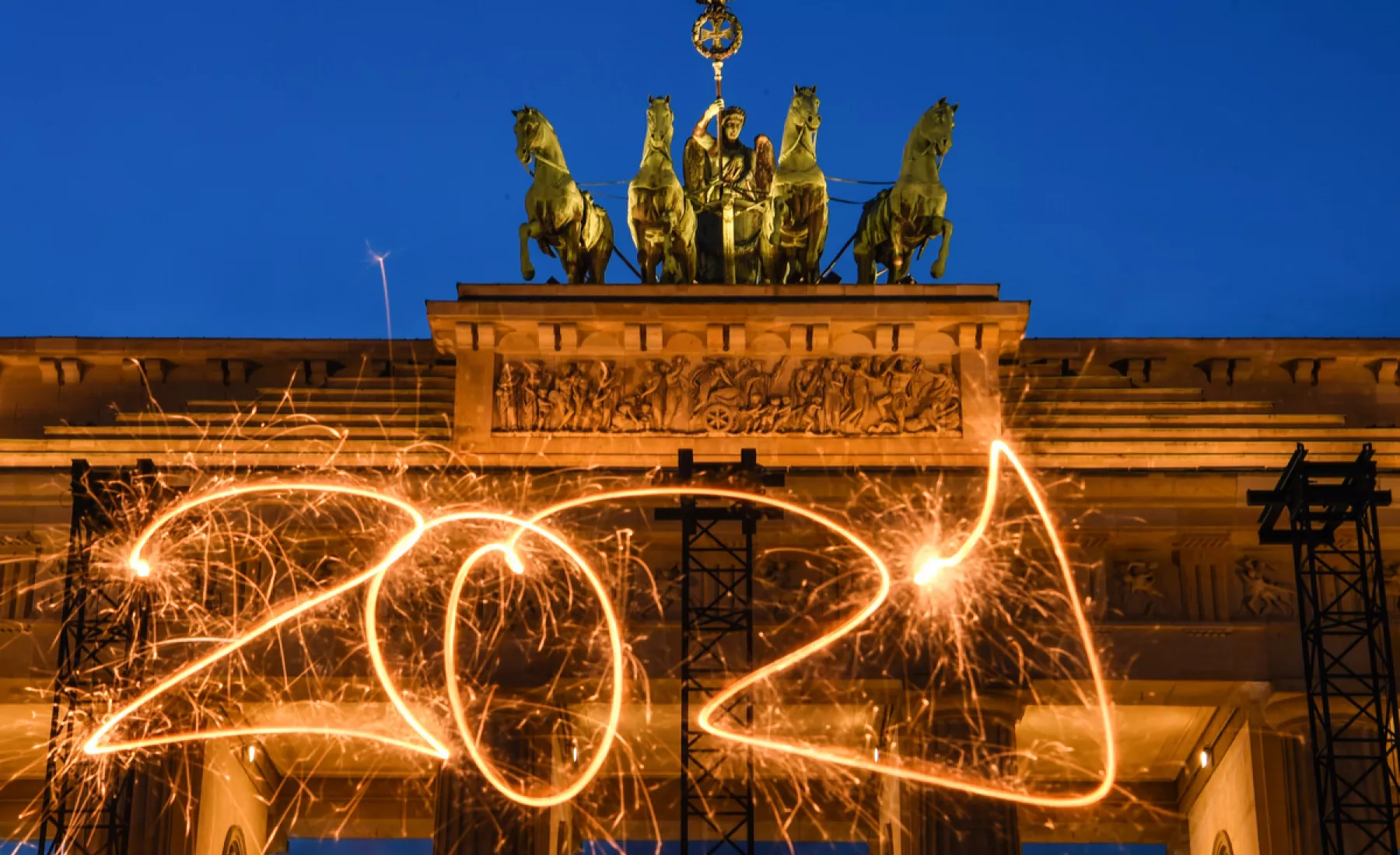 Die Zahl 2021 ist mit einer Wunderkerze während einer Langzeitbelichtung vor dem Brandenburger Tor in den Abendhimmel geschrieben.