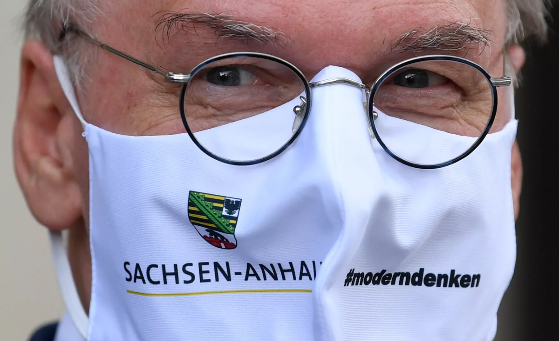 Reiner Haseloff (CDU), Ministerpräsident von Sachsen-Anhalt, trägt eine Maske mit dem Wappen des Landes