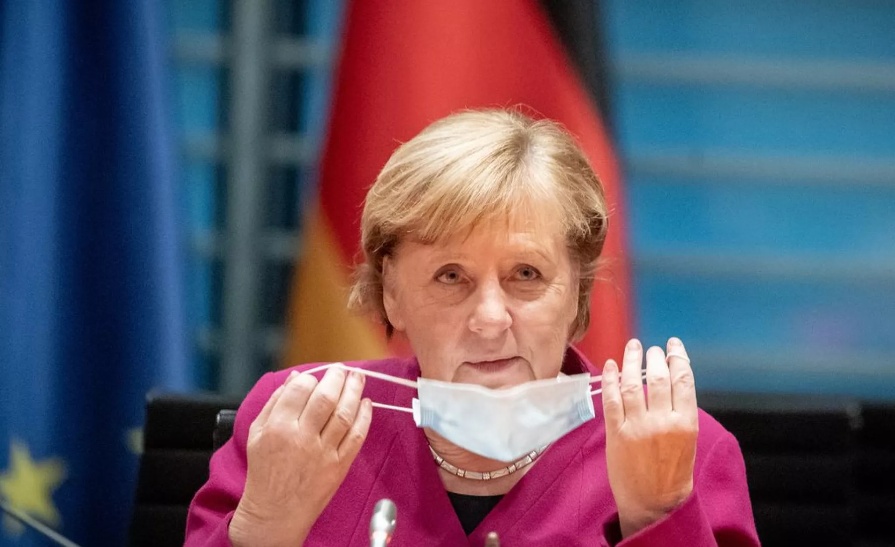 Angela Merkel setzt einen Mundschutz auf