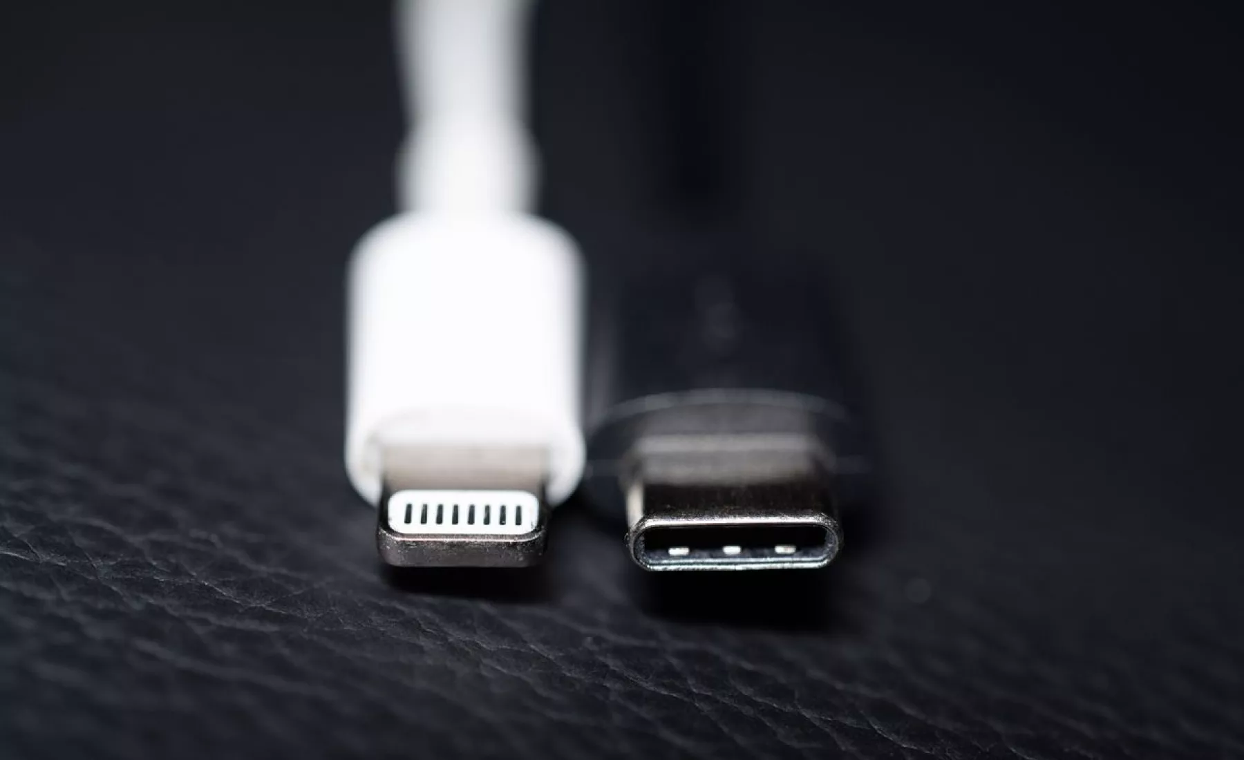 Ein Apple Lightning Ladestecker (l) ist neben einem USB-C Ladestecker zu sehen