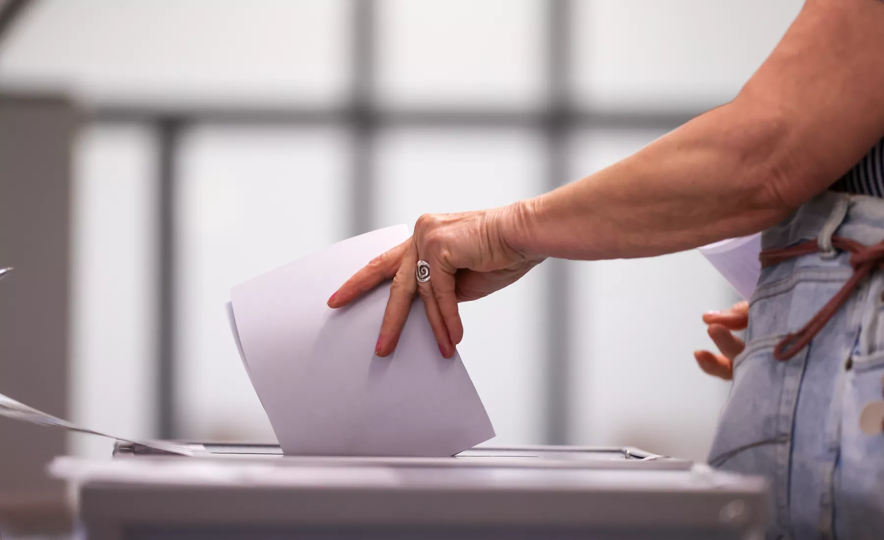 Frau wirft Stimmzettel in Urne im Wahllokal