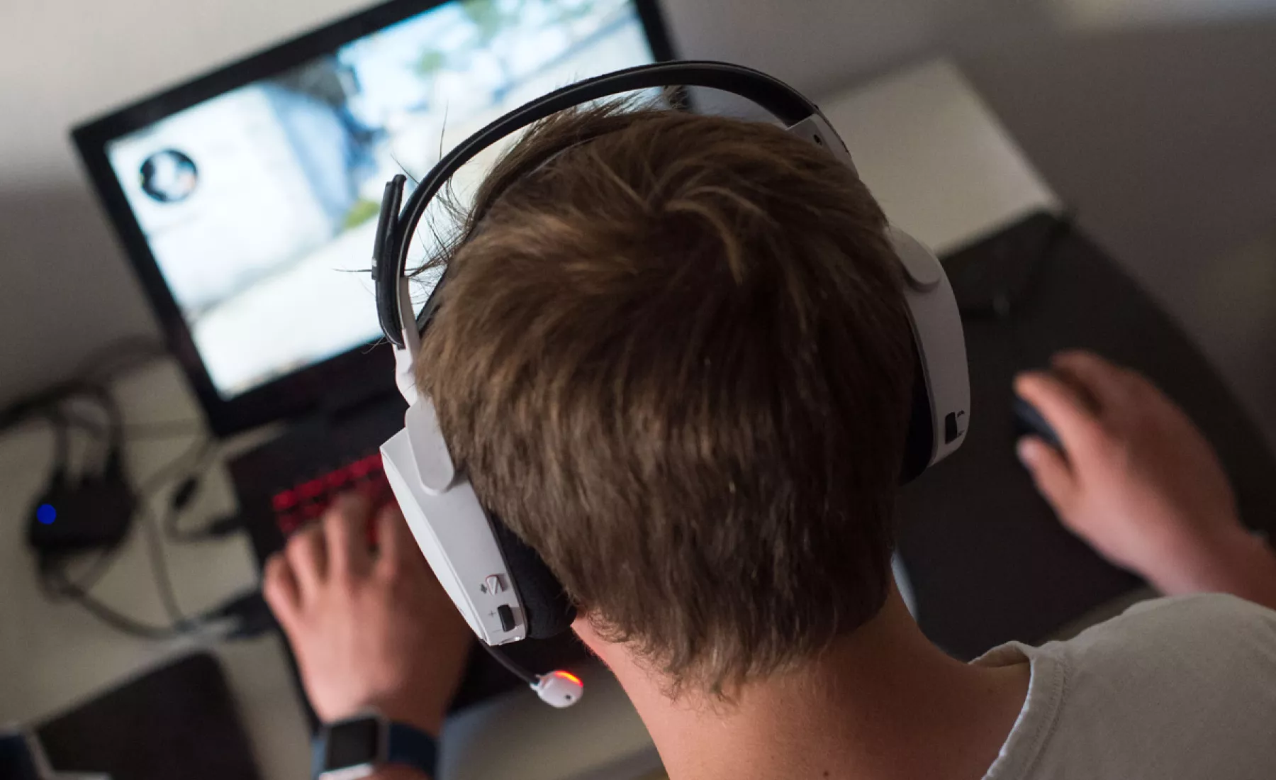 Ein Mann sitzt mit einem Headset vor einem Laptop und spielt ein Online-Computerspiel. 