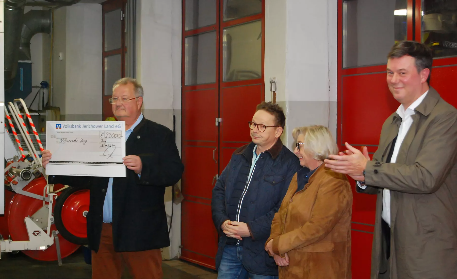 Kay-Ebe Schnoor präsentiert den angetretenen Mitglieder der Freiwilligen Ortsfeuerwehr Burg den Spendenscheck.