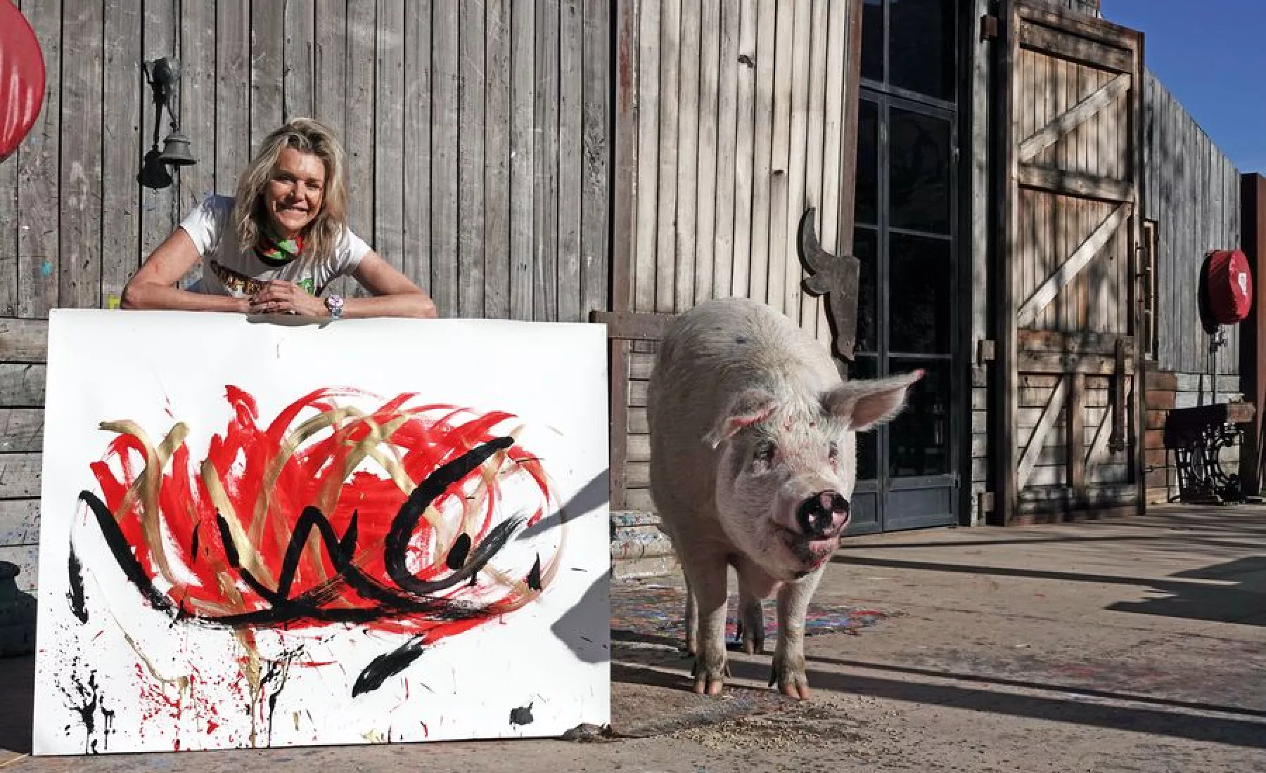 Pigcasso, ein malendes Schwein aus Südafrika, steht mit seiner Halterin Joanne Lefson neben einem Bild, das es gemalt hat