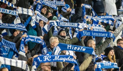 02.02.2024, Sachsen-Anhalt, Magdeburg: Fußball: 2. Bundesliga, 1. FC Magdeburg - Holstein Kiel, 20. Spieltag, MDCC-Arena.Fans von 1. FC Magdeburg feuern ihr Team an und halten ihre Schals hoch.