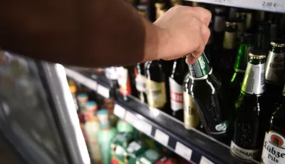Ein Mann holt eine Flasche Bier aus einem Kühlschrank in einem Spätkauf