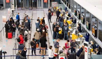 Passagiere stehen am Flughafen München an einem Check-In-Schalter