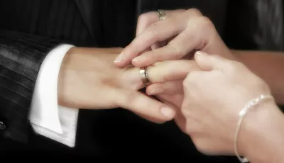 Eine Frau steckt einem Mann einen Ehering an dessen Finger