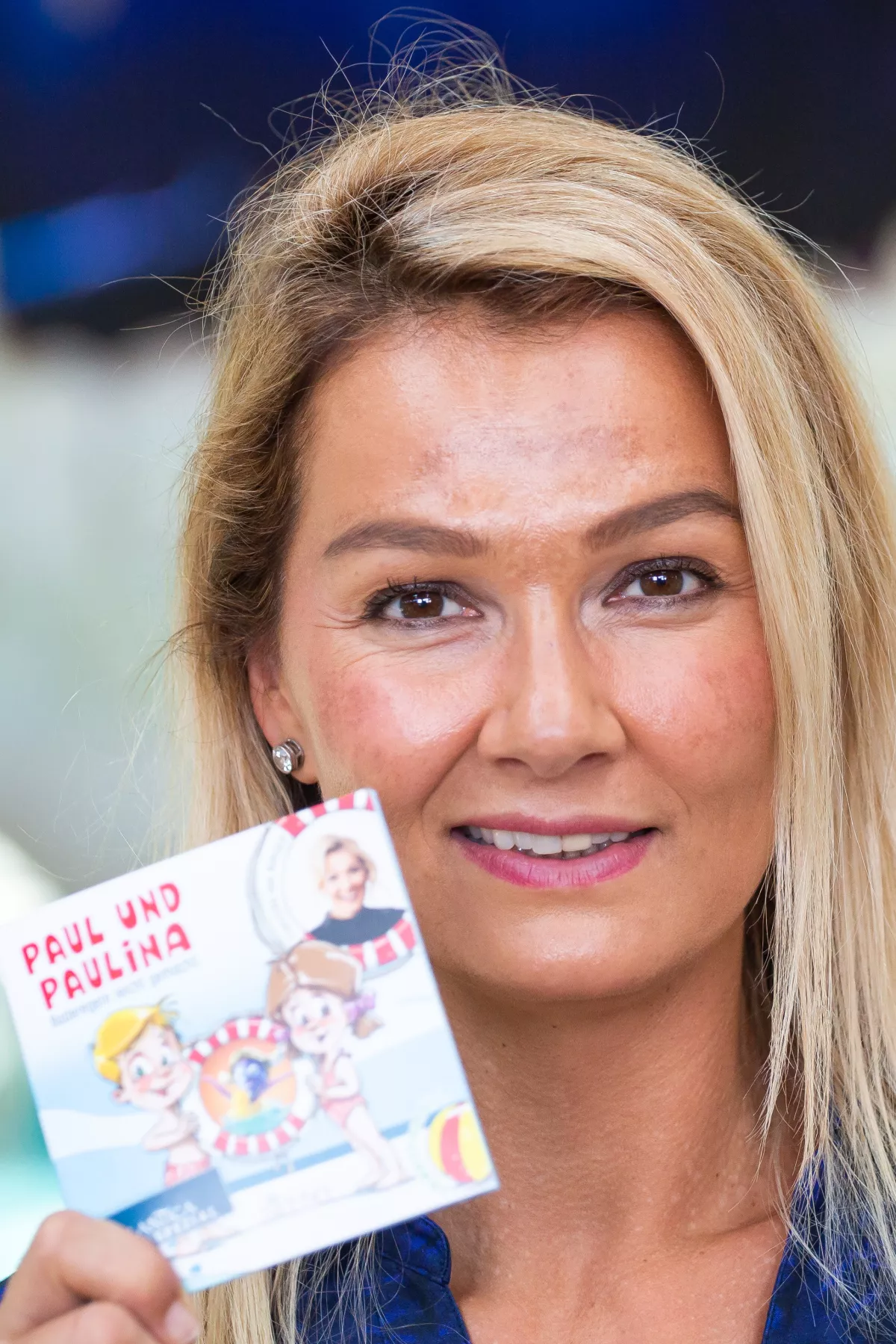 Franziska van Almsick steht im Erlebnisbad Rulantica und hält ein Exemplar ihres Buches "Paul und Paulina - Baderegeln leicht gemacht" in der Hand.