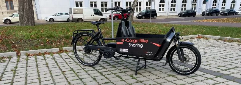 Schwarzes Lastenrad mit Aufschrift "e-Cargo Bike Sharing"