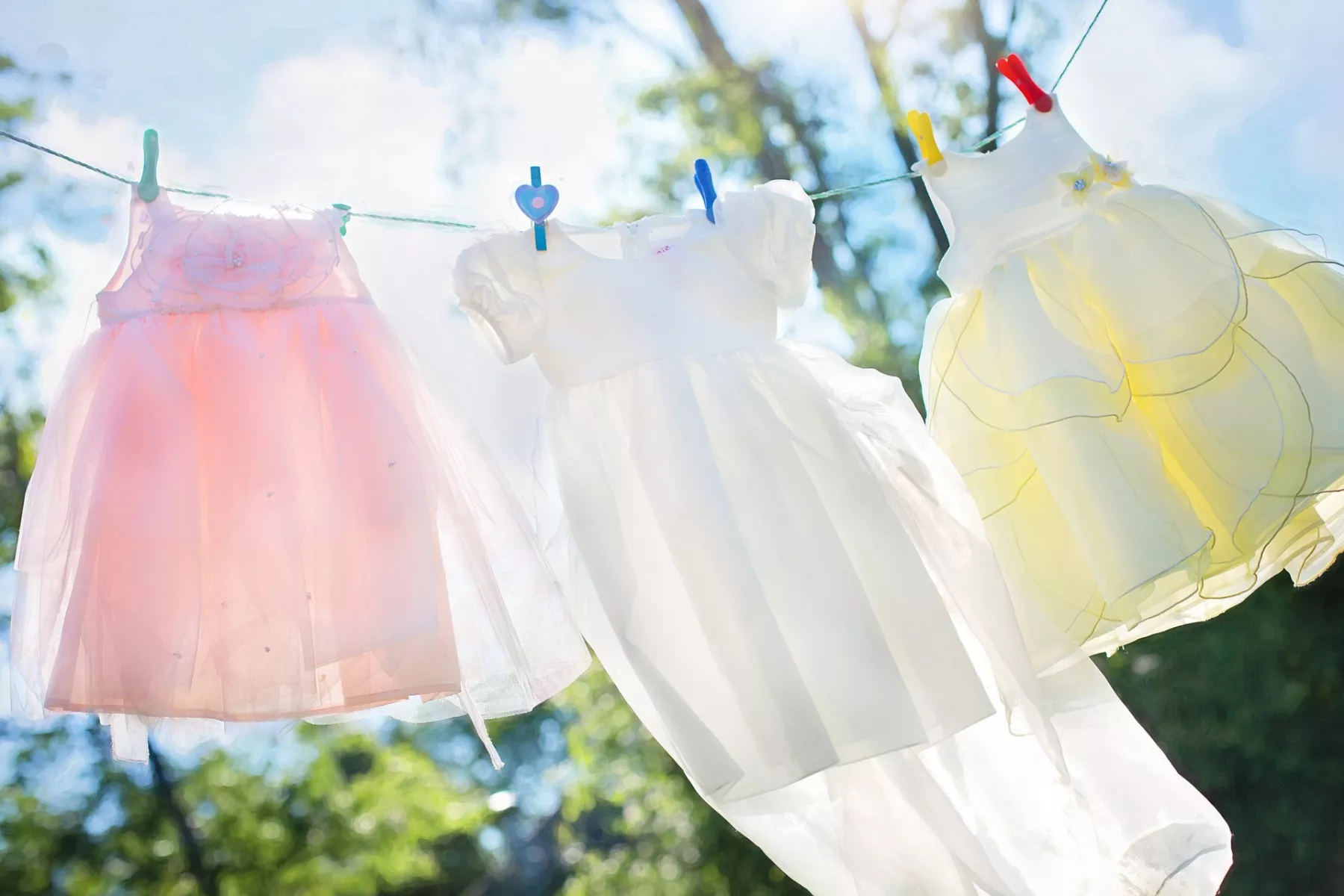 Pastellfarbene Wäsche hängt im strahlenden Sonnenschein auf einer Wäscheleine