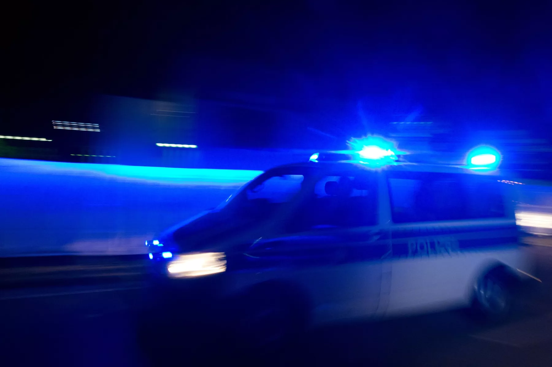 Symbolbild: Ein Polizeiwagen fährt in der Dunkelheit mit Blaulicht. 