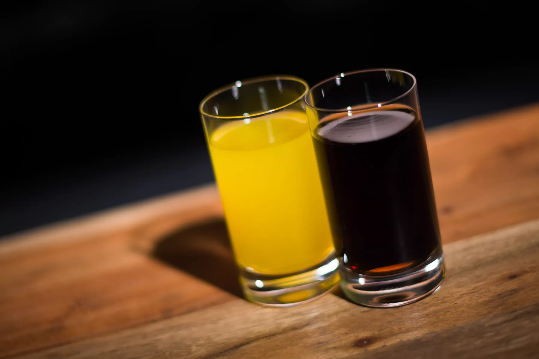 Ein Glas mit Cola steht neben einem Glas mit Orangenlimonade